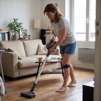 Femme passant l'aspirateur avec la sangle rotulienne au genou